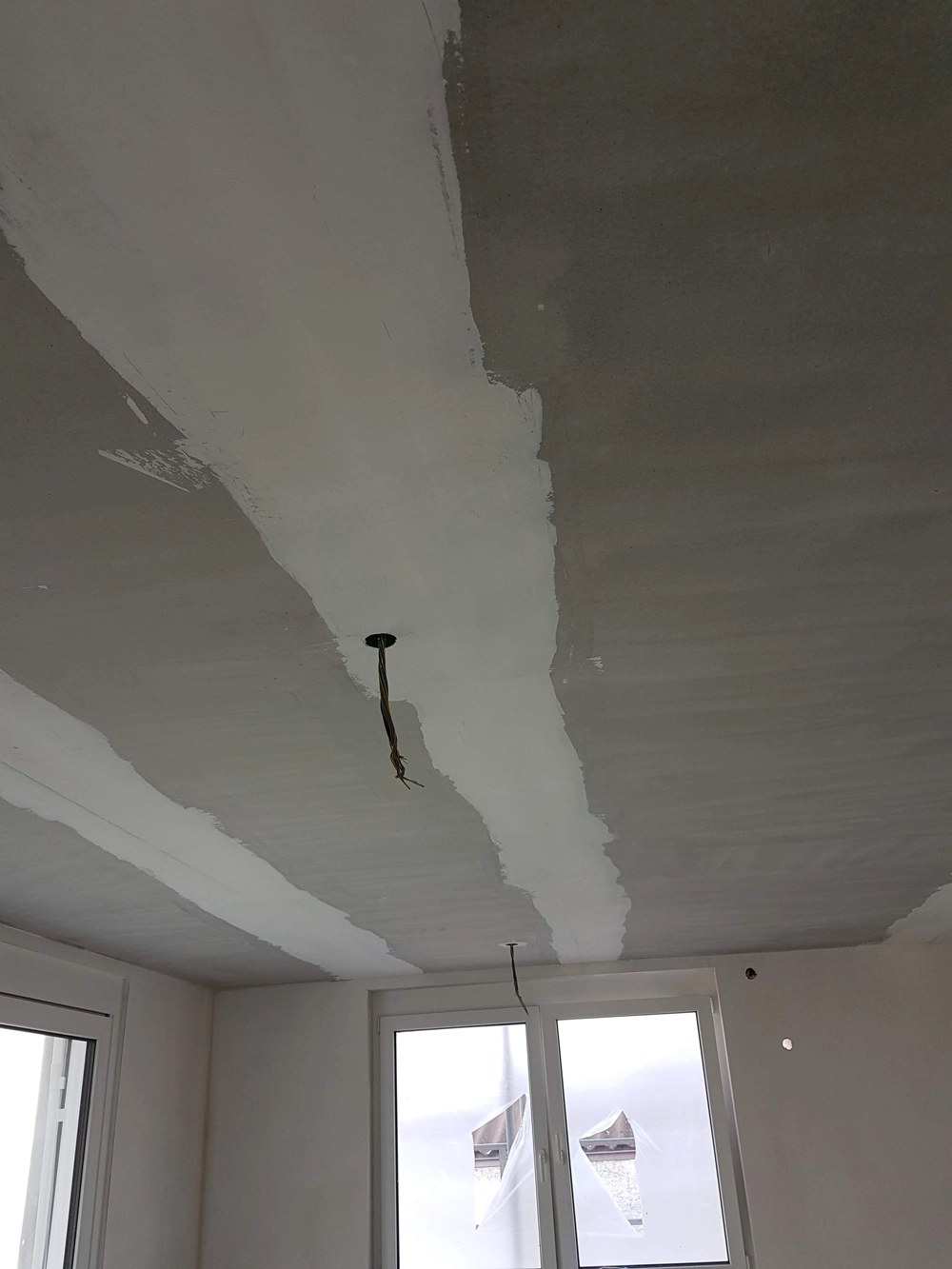 Sufit po szpachlowaniu płyt gipsowo-kartonowych z kablem oświetleniowym i osłoniętymi oknami