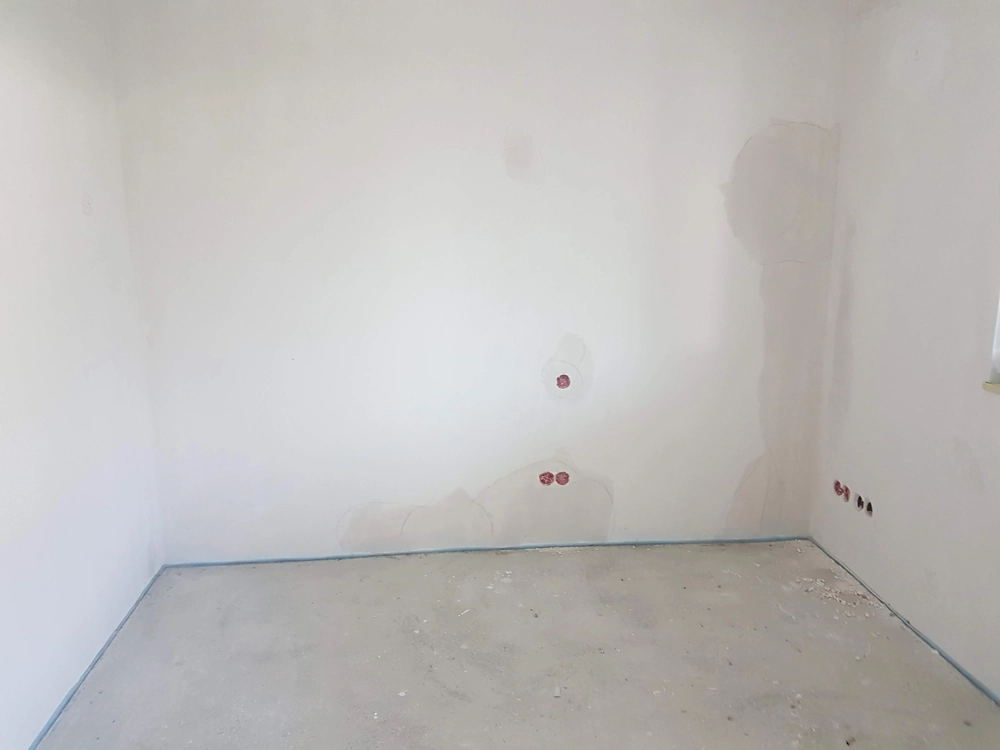 Gładzie wykonane w pustym pokoju ze ścianami wygładzonymi z otworami na gniazda elektryczne