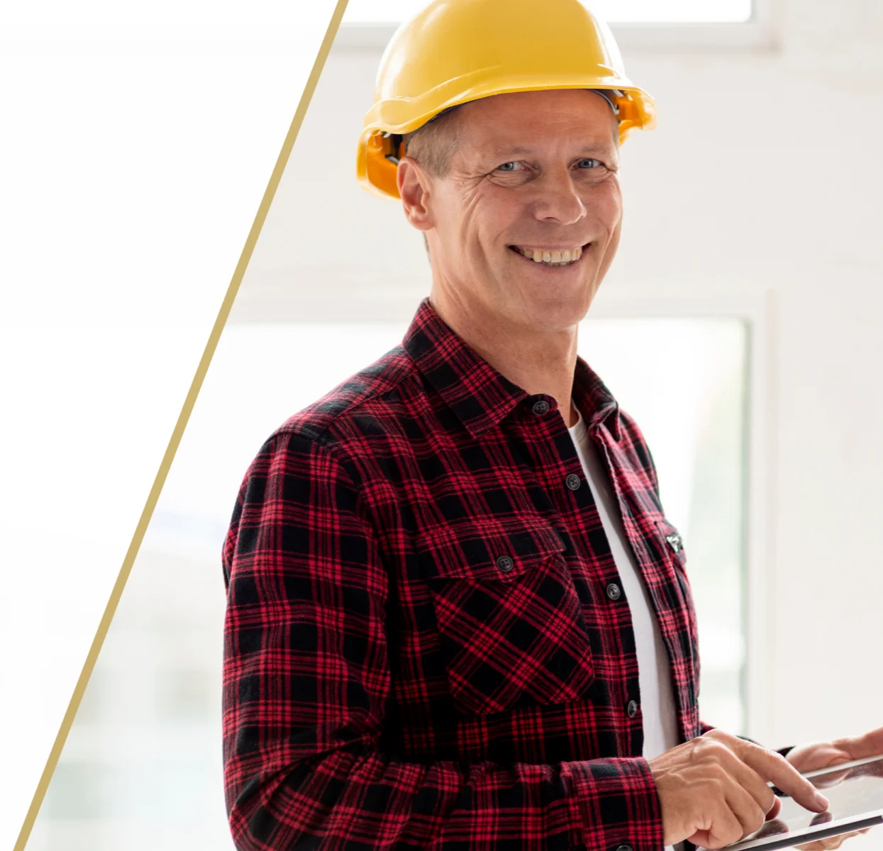 Mężczyzna w żółtym kasku i czerwonej koszuli flanelowej kontroluje prace wykończeniowe wnętrza, korzystając z tabletu